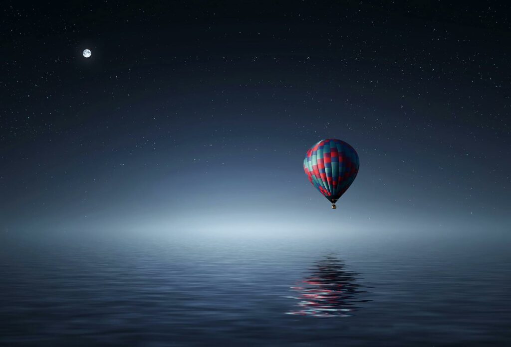 A serene hot air balloon floating over the ocean under a starry night sky.