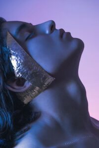 Creative portrait featuring a person with a metallic square element against a vibrant backdrop.