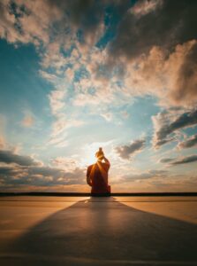 Silhouette of a figure meditating against a stunning sunset sky, creating a serene and peaceful atmosphere.