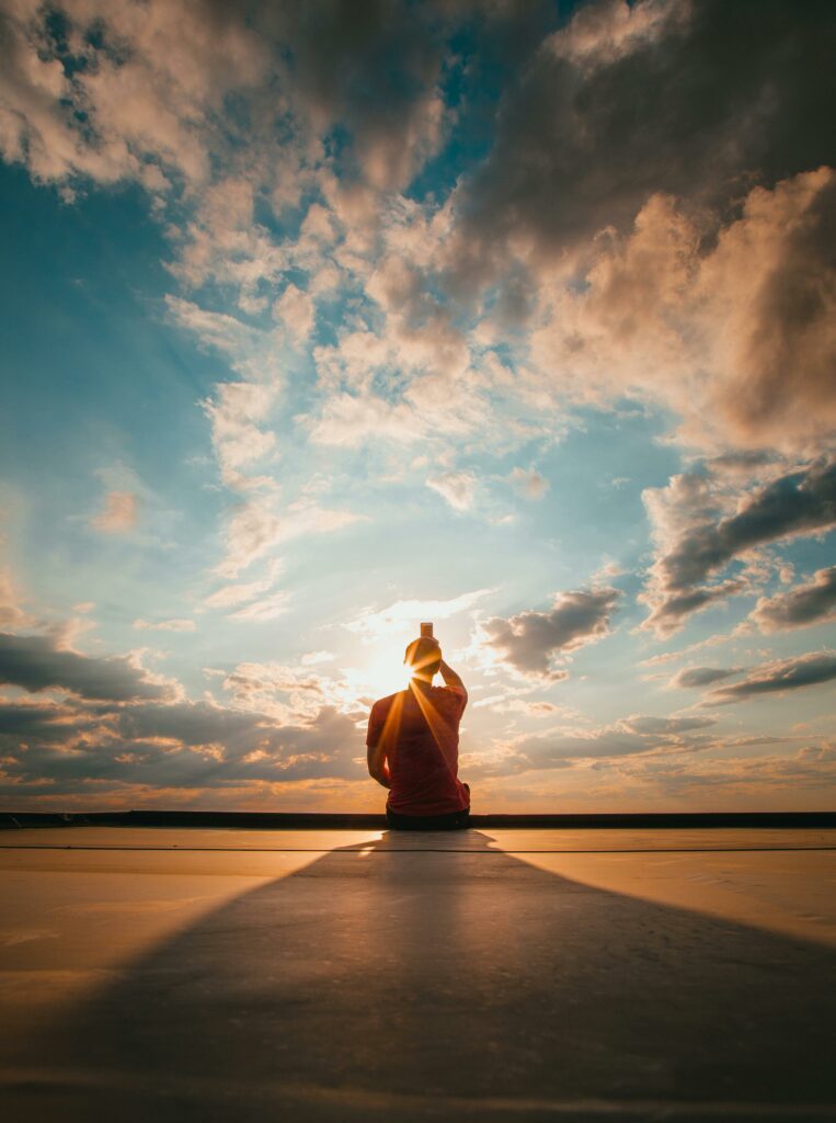 Silhouette of a figure meditating against a stunning sunset sky, creating a serene and peaceful atmosphere.