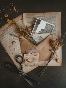 Charming vintage arrangement with dry flowers, envelopes, and old photographs in a rustic setting.