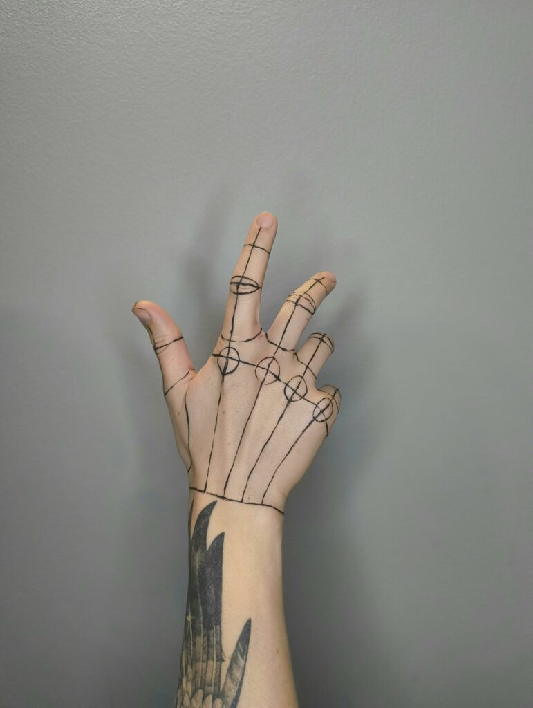 Close-up of a hand with artistic line drawing, showcasing anatomy on tattooed skin.