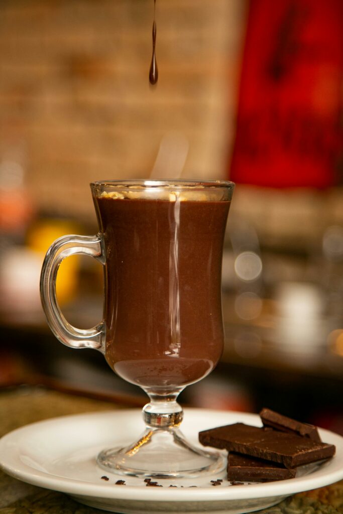 Rich hot chocolate served in a glass mug with chocolate pieces on the side, perfect treat.