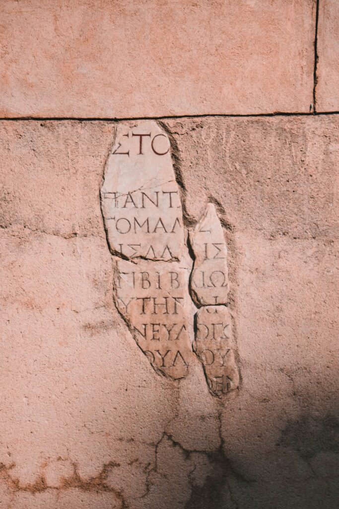 Ancient Greek text inscribed on a weathered stone wall, showcasing historic writing.