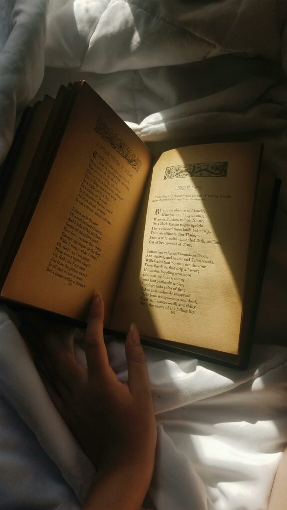 A hand gracefully holds an open book, revealing poetic verses under soft light.