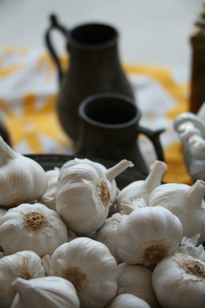 A rustic kitchen scene with fresh garlic cloves and vintage pitchers in soft focus.
