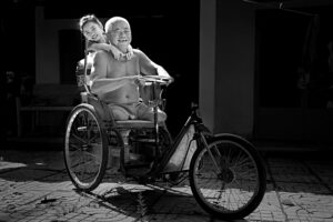 A joyful moment of a father and child on a tricycle, captured in black and white.