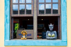 Vibrant window display featuring vivid sculptures in a rustic setting.