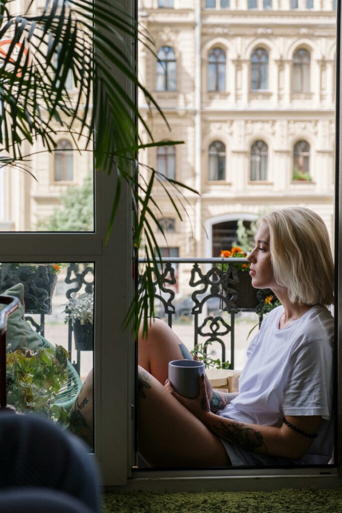 A serene moment of relaxation on an urban balcony as woman enjoys coffee.