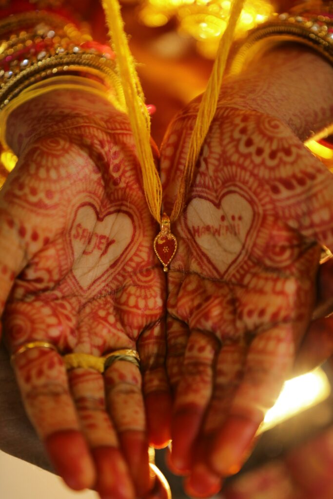 Close-up of traditional bridal henna with heart designs on palms, evocative of cultural beauty.