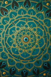 Detailed dot painting mandala artwork on teal background showcasing vibrant, intricate patterns.