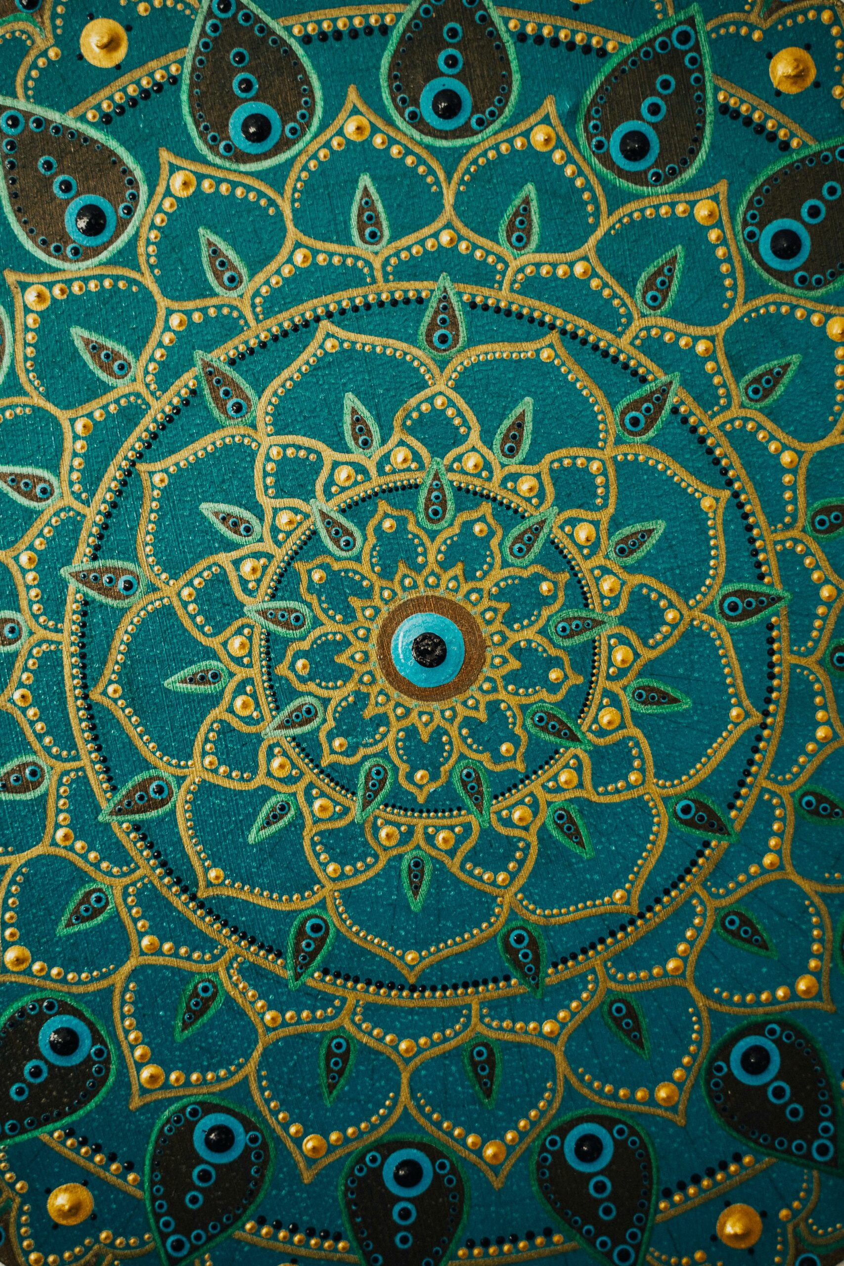 Detailed dot painting mandala artwork on teal background showcasing vibrant, intricate patterns.