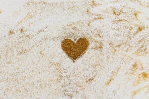 Golden glitter forms a heart shape on a textured white background.
