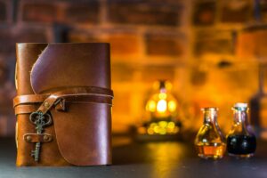 Leather journal with vintage key and potion bottles on rustic background.