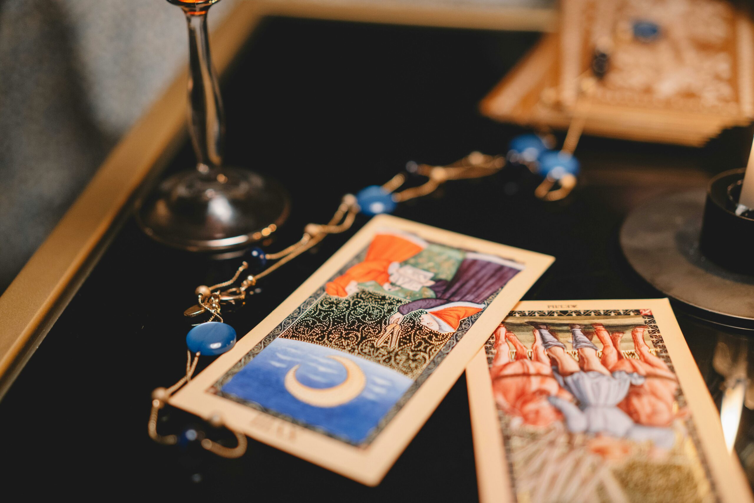 Close-up view of tarot cards on a table with a wineglass and mystical elements.