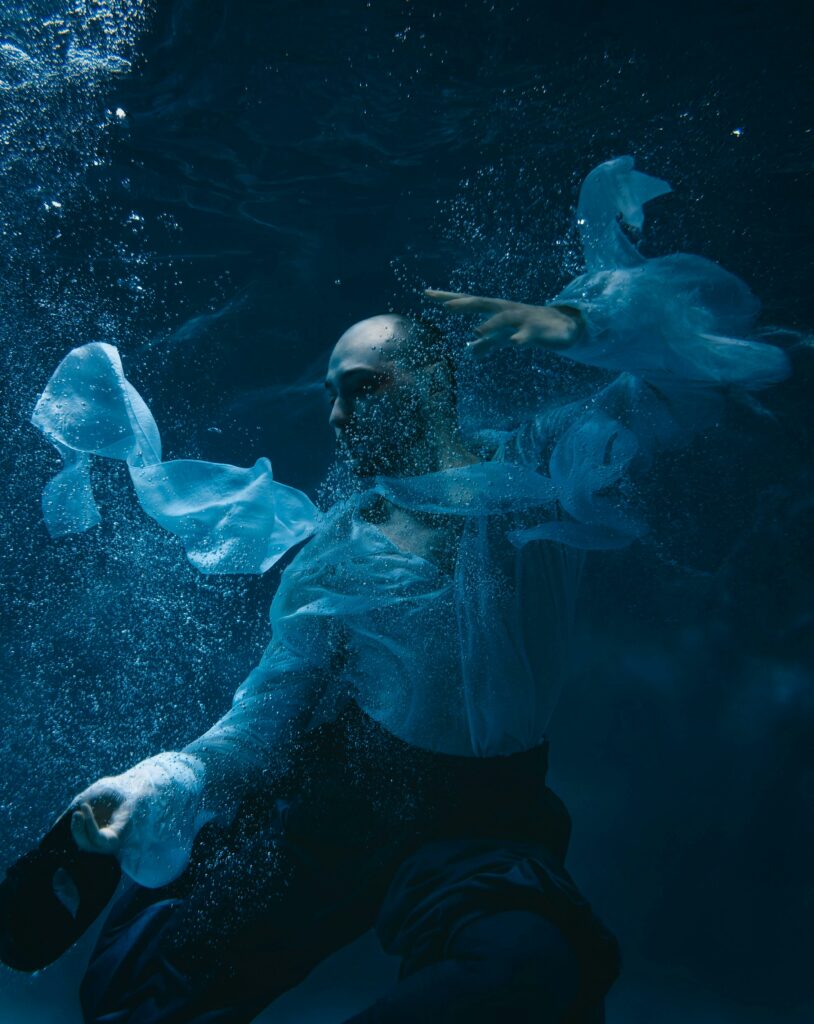 Artistic underwater photo of a man in flowing attire, capturing elegance and movement.