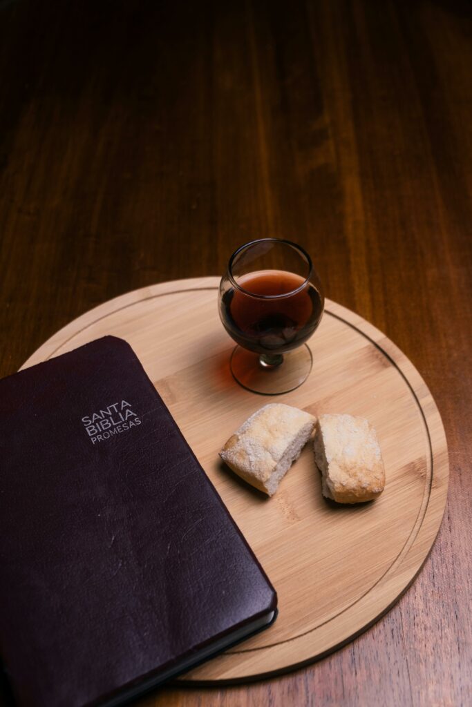 A Santa Biblia, bread, and glass of wine on a wooden tray symbolize a communion setting.