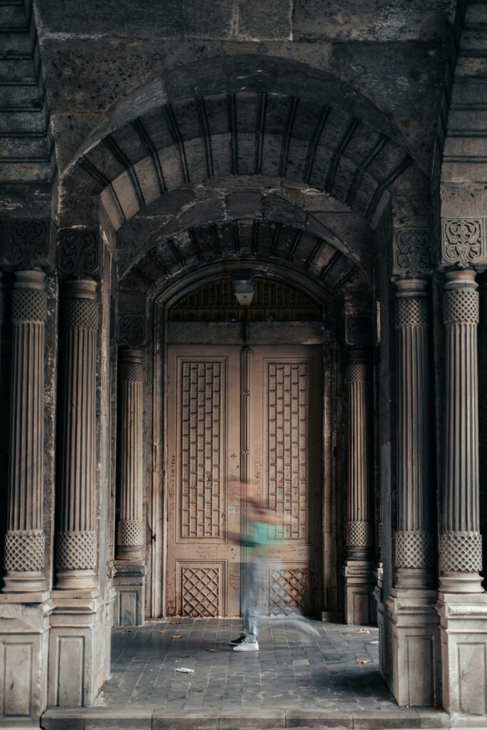Blurred motion of a person running through a historic entrance with ornate arches and columns.