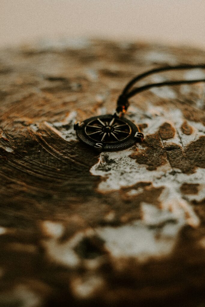 A detailed photograph capturing a compass pendant lying on a textured wooden surface, evoking adventure and exploration.