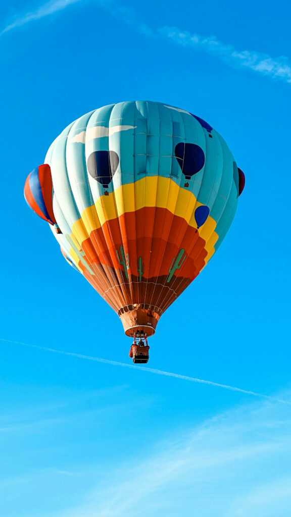 Vibrant hot air balloon soaring against a clear blue sky.