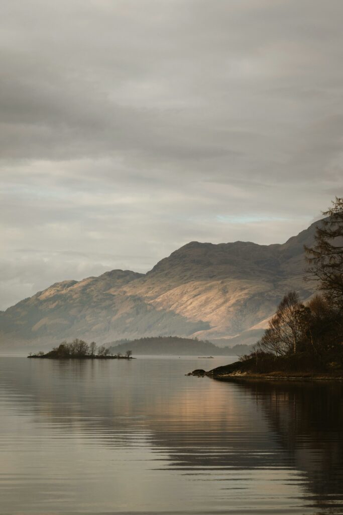 Misty morning view of Loch Lomond with mountains and calm waters in Scotland.