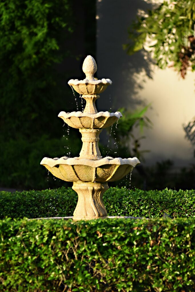 A beautiful three-tier stone fountain with water flowing in a lush garden setting.