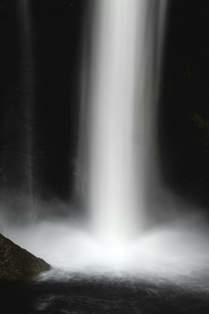 A serene and powerful waterfall cascading into a calm pool in a tranquil natural scene.