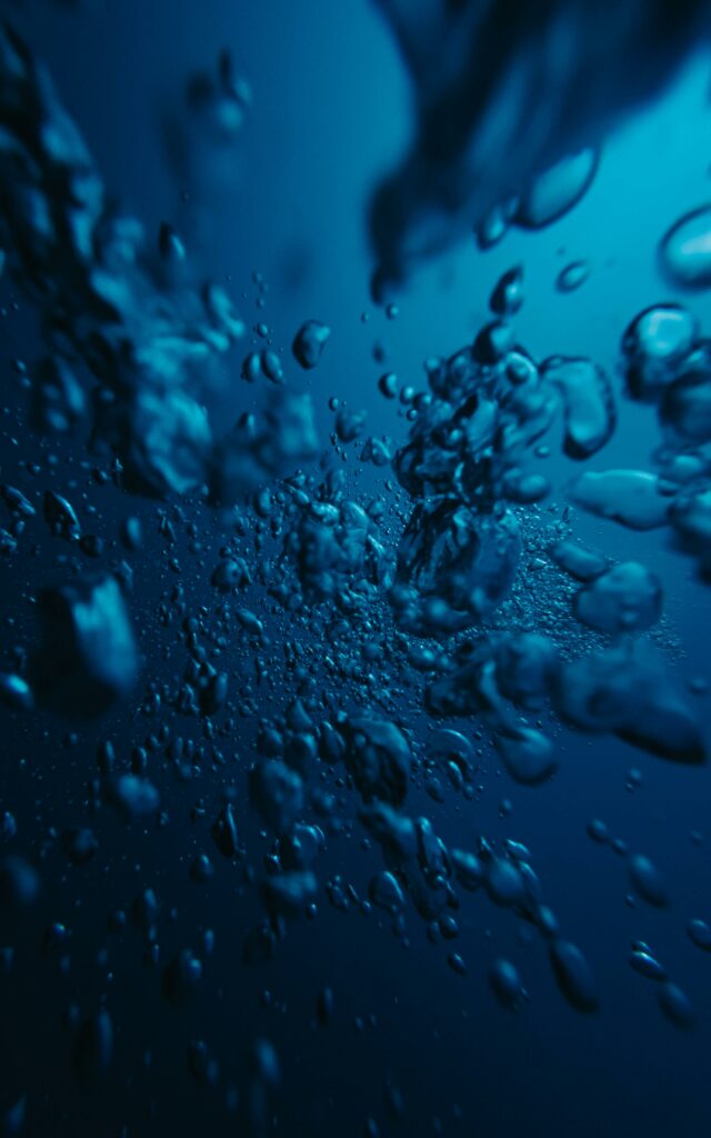 Abstract image of bubbles rising in deep blue water creating a soothing feel.