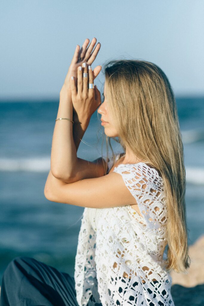 Serene young woman practicing yoga on the beach, embracing calmness and nature.