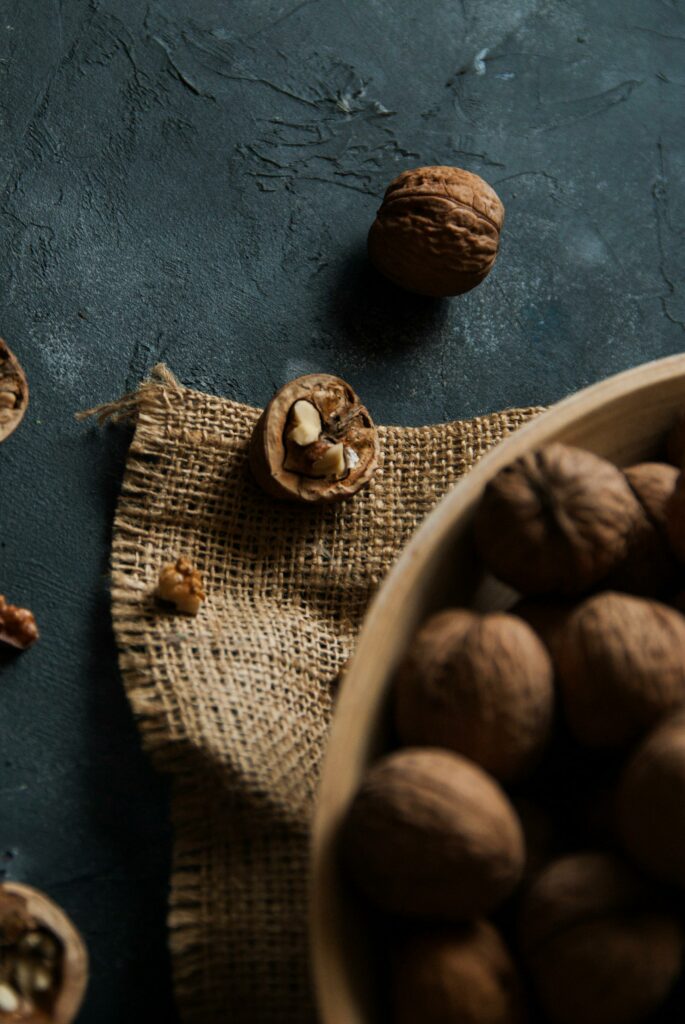 Close-up photo of cracked walnuts on a textured burlap surface, providing a rustic feel.