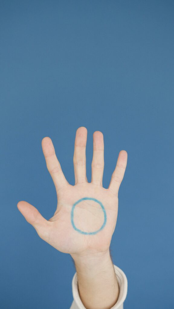 Open hand with a blue circle drawn on palm against a blue background, vertical shot.