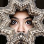 Close-up of a woman's eyes peering through a decorative lattice in New Delhi, India. pexels-photo-693816-693816