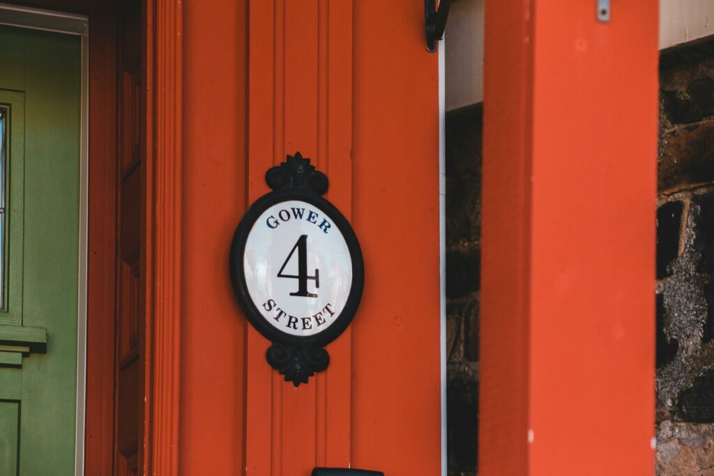 Exterior of aged residential house with wooden door and signboard with inscription placed on bright red wall on street
