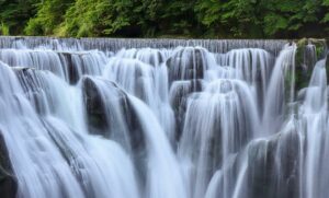 Serene long exposure of a cascading waterfall surrounded by lush greenery in Shifen, Taiwan.