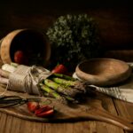 A rustic arrangement of asparagus and strawberries on a wooden board, captured in warm tones.