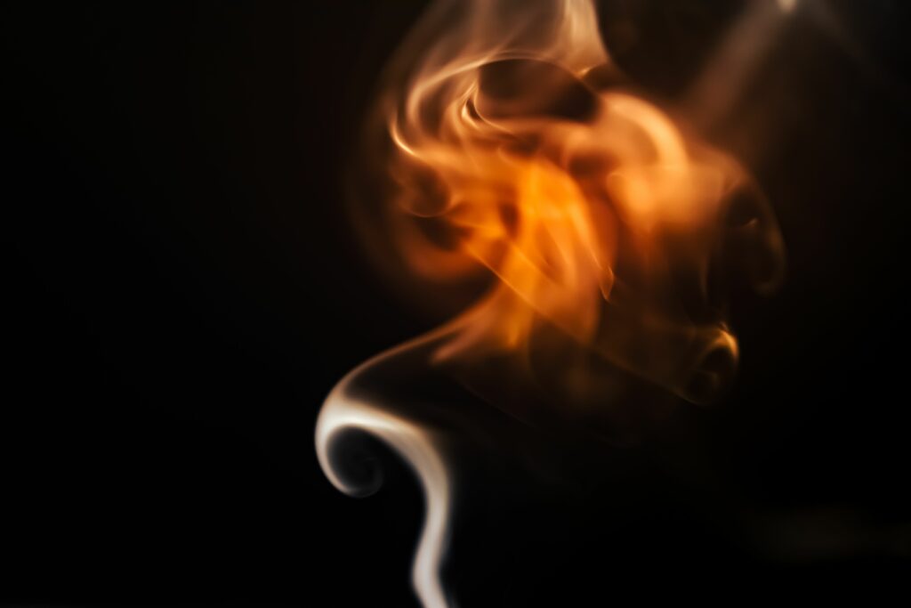 A captivating abstract image of flame and smoke swirling in a dark background, showcasing vibrant colors and fluid movement.