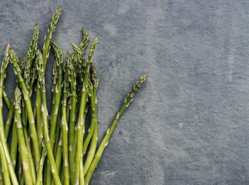 Close-up of fresh asparagus stalks on a textured slate background, perfect for health and food themes.
