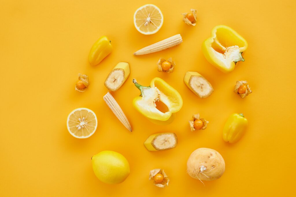 A colorful flat lay of yellow fruits and vegetables on a matching yellow background for a fresh and vibrant look.