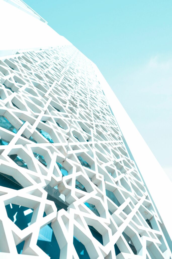 Modern building facade with intricate geometric patterns and bright blue sky background.