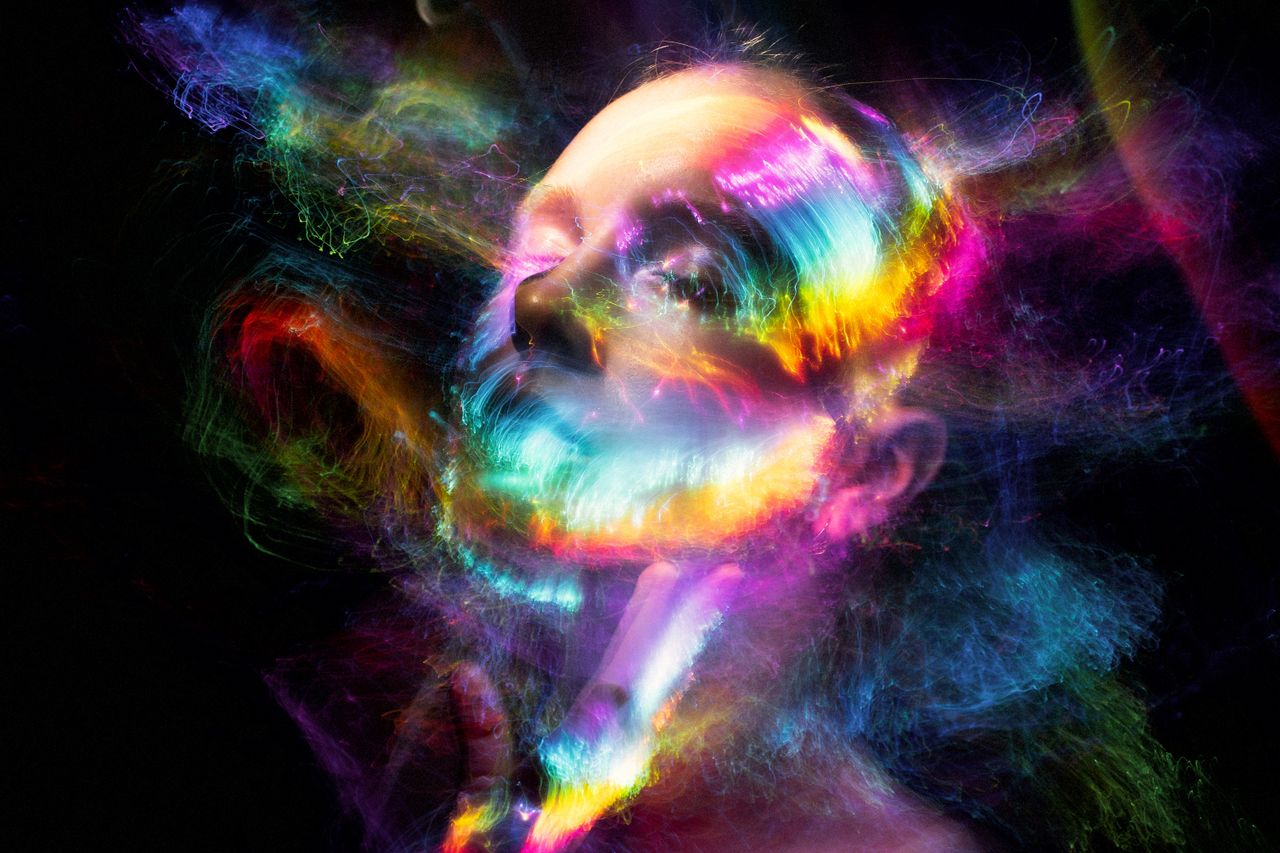 A mesmerizing abstract portrait featuring dynamic, colorful light effects swirling around a woman's face.