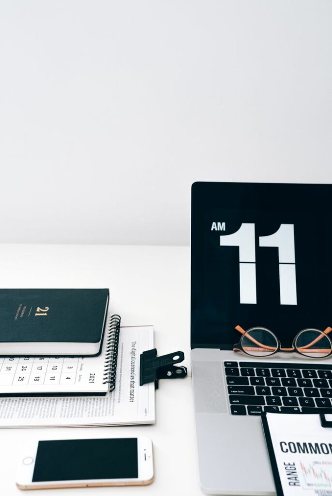 A clean desktop featuring a laptop, smartphone, calendar, and digital clock at 11 AM.