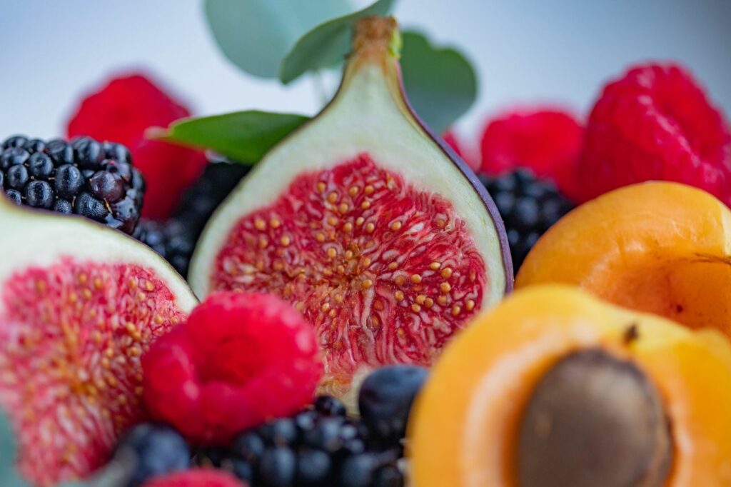 Close-up of fresh figs, berries, and apricot, highlighting their vibrant colors and textures.