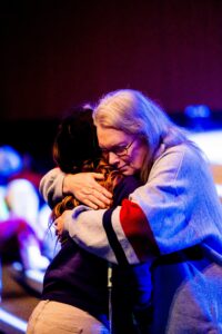 Two adults share a comforting hug in a warm, supportive environment. Emotional connection.