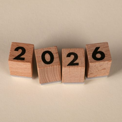 Wooden cubes forming the year 2026 on a neutral background.