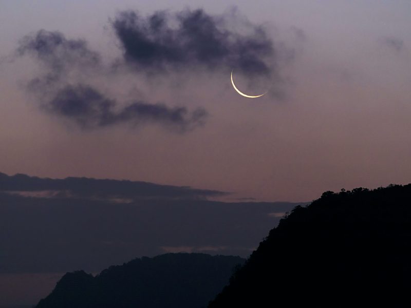 Crescent moon with dark clouds in twilight sky over Phang-nga, Thailand.