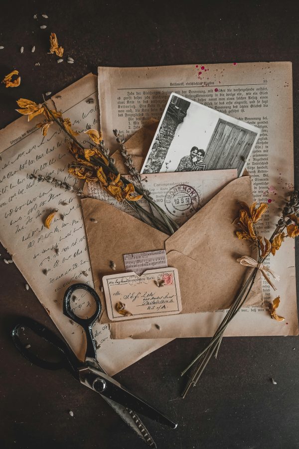 Charming vintage arrangement with dry flowers, envelopes, and old photographs in a rustic setting.